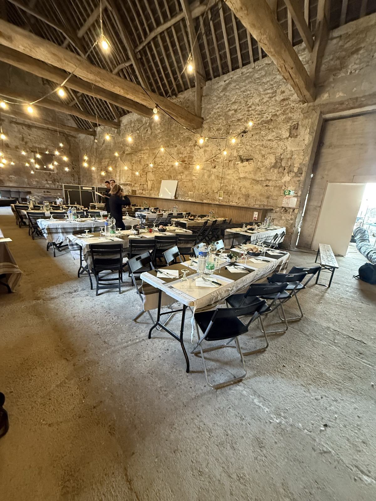 La grange dressée en cantine de tournage : guirlandes et grandes tablées