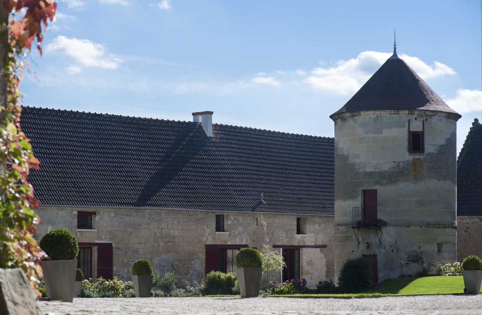 La cour de L’Instant à Morienval et ses deux tours de pierre sous un ciel bleu