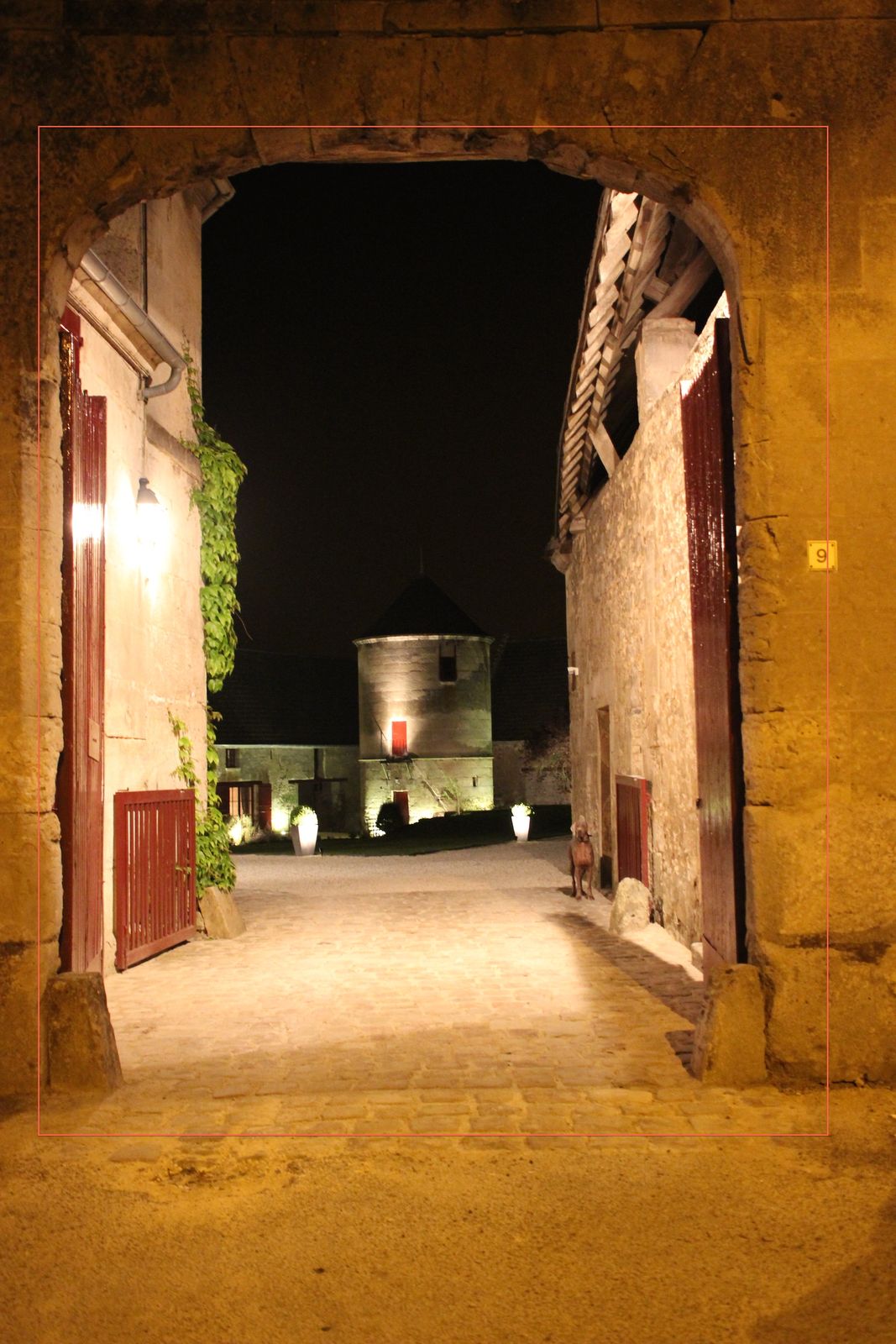 Le porche la nuit, le pigeonnier éclairé au fond